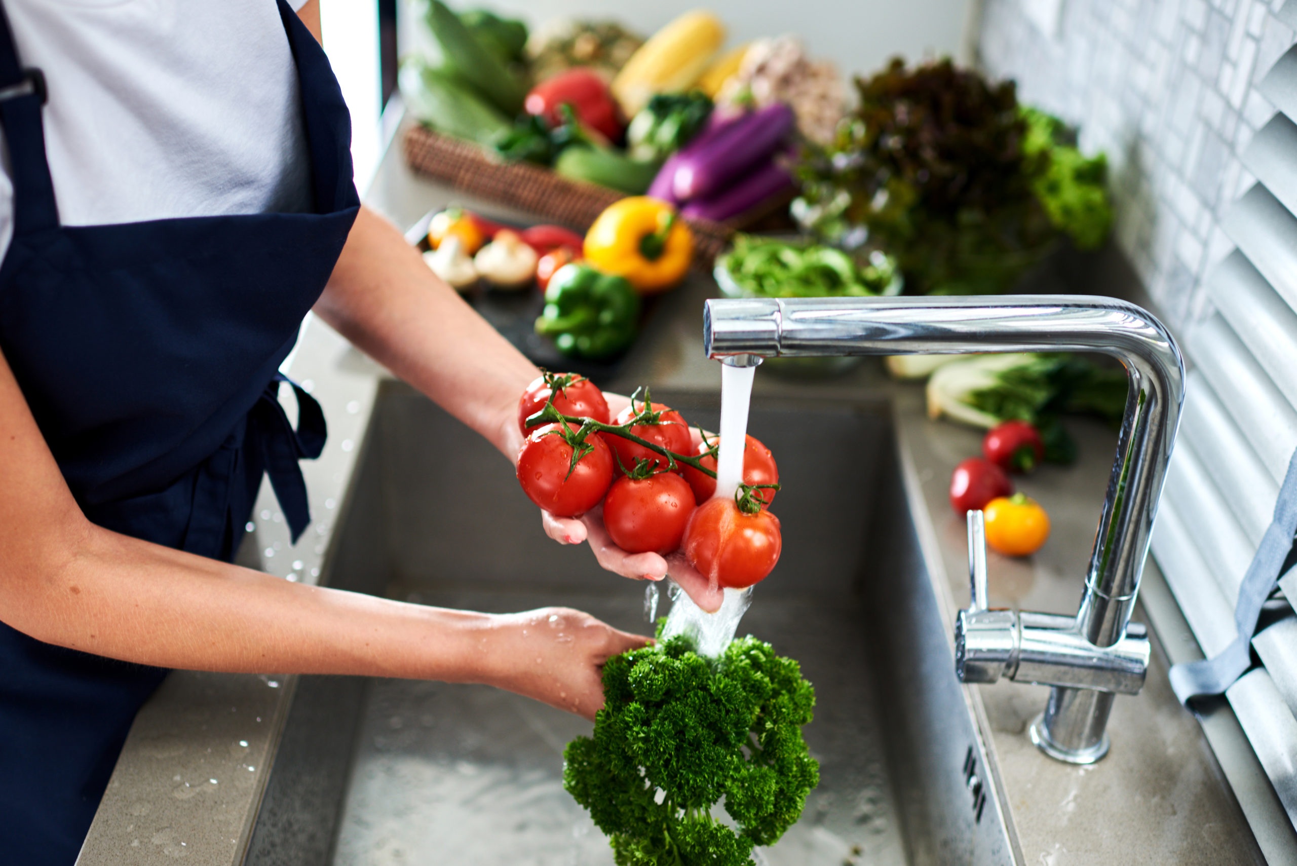 Woman washing vegetables broccoli and tomatoes