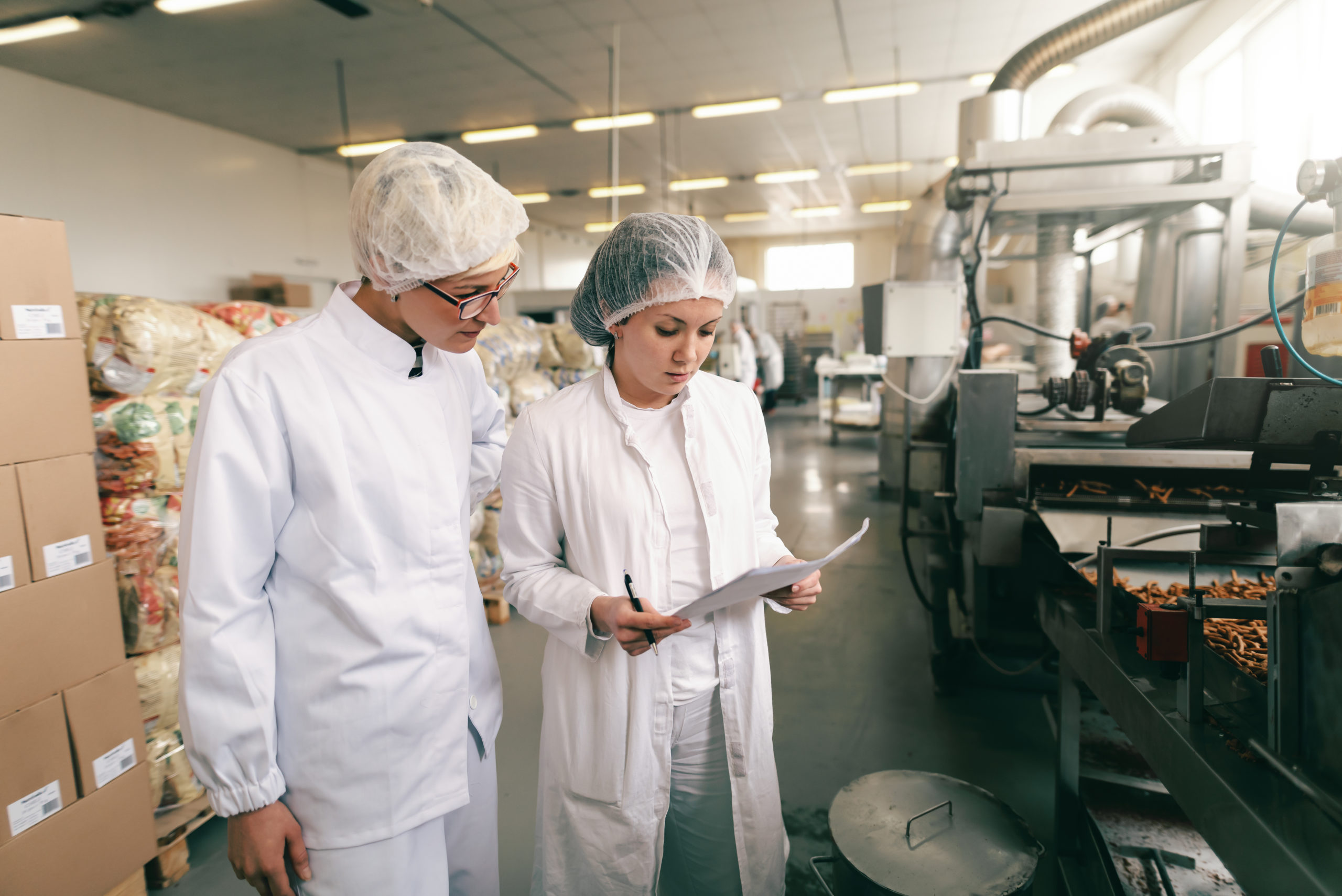 Two professionals in white sterile uniforms at food factory